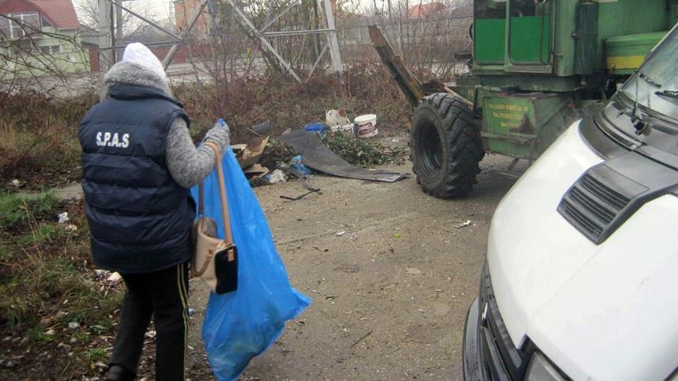 O asistată social, scoasă la muncă, adună mizeria cu poșeta pe braț